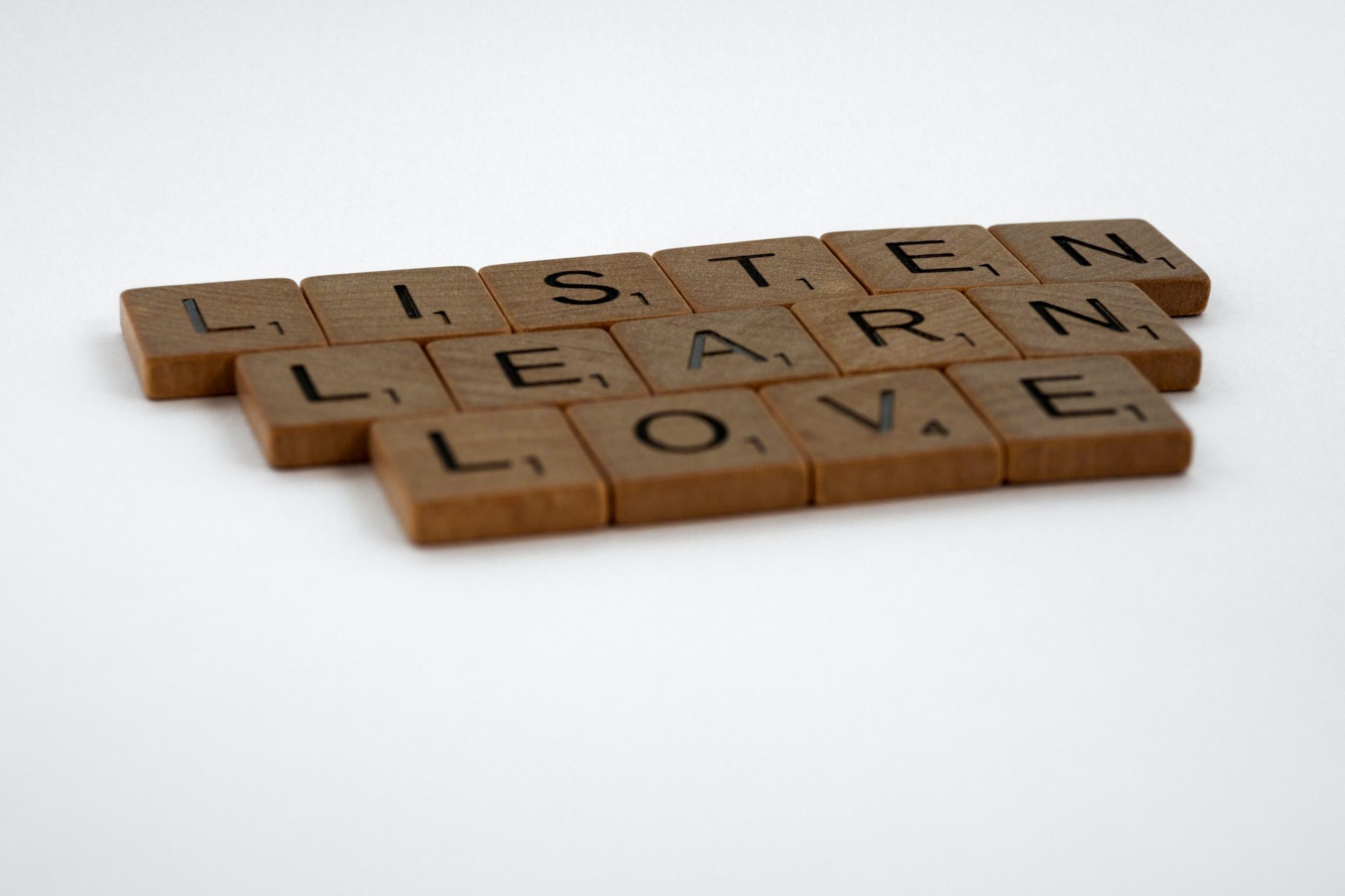 Scrabble-Steine die die Worte Listen, learn, love buchstabieren